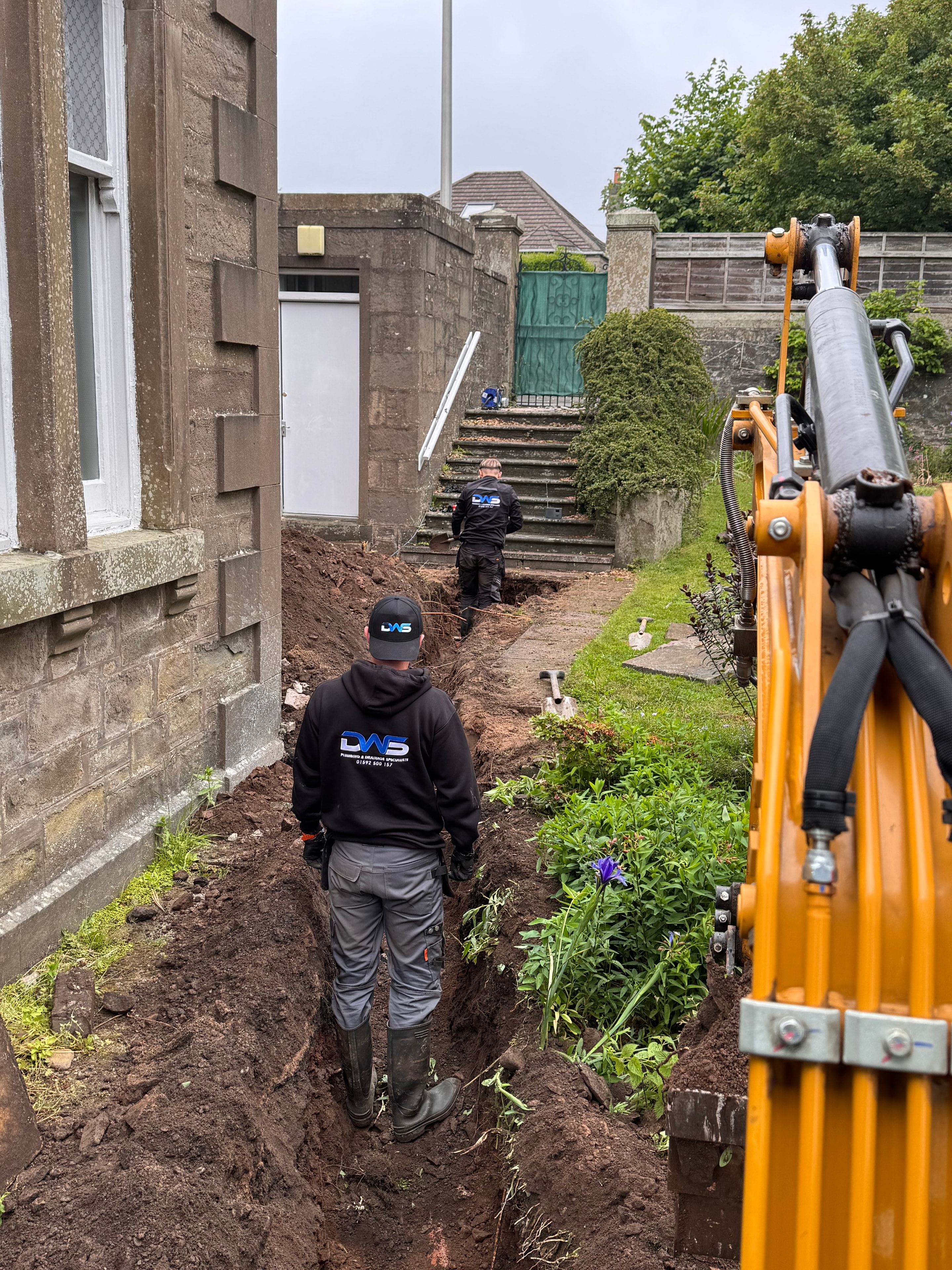 Completed drainage repair excavation beside a residential property